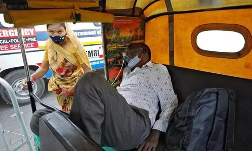 man sitting in auto rickshaw with oxygen cylinder