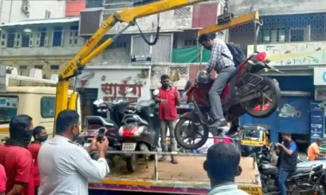 Pune Traffic Police officials tow bike with the owner sitting on it