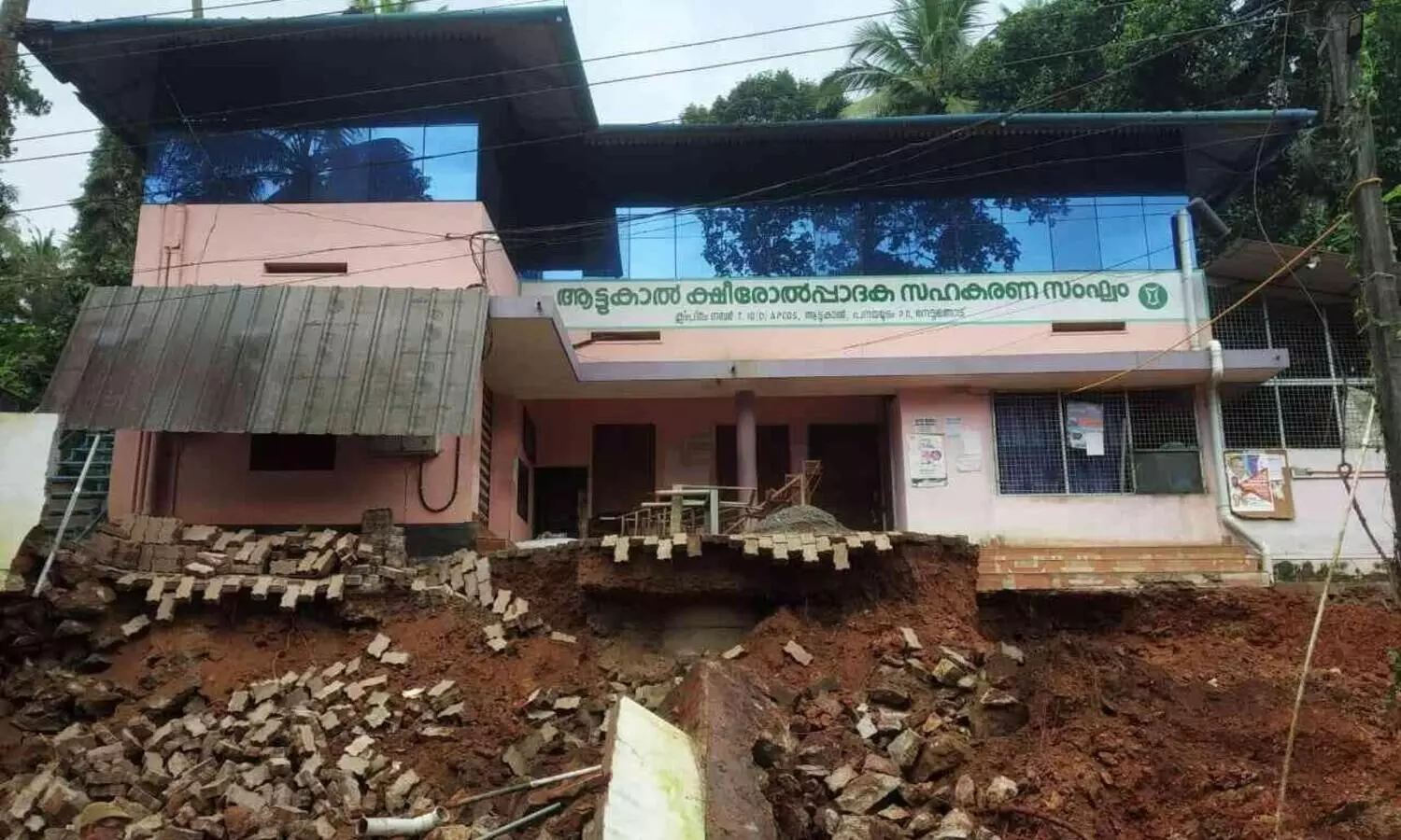 റോഡ് പണിക്കായി എസ്‌കവറ്റർ കൊണ്ട് ചുറ്റുമതിലിന്‍റെ അടിവാരം തോണ്ടി ക്ഷീര സംഘം മന്ദിരം തകർന്നു