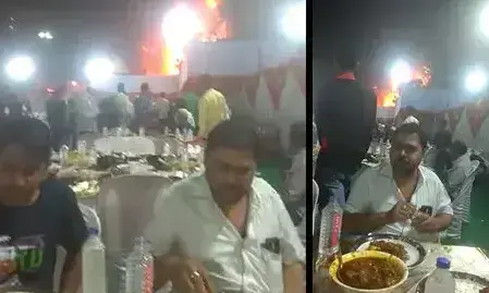 വിവാഹ പന്തൽ പിറകിൽ  കത്തിയമരുമ്പോഴും ഭക്ഷണം കഴിക്കുന്ന രണ്ടുപേർ