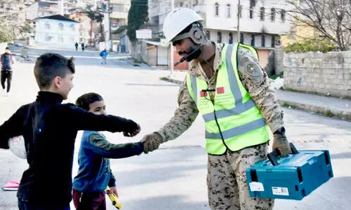 ദു​ര​ന്ത​ഭൂ​മി​യി​ൽ ര​ക്ഷാ​ദൗ​ത്യ​ത്തി​ലേ​ർ​പ്പെ​ട്ട റോ​യ​ൽ ഗാ​ർ​ഡ് സേ​നാം​ഗ​ത്തി​ന് ഹ​സ്ത​ദാ​നം ചെ​യ്യു​ന്ന കു​ട്ടി​ക​ൾ