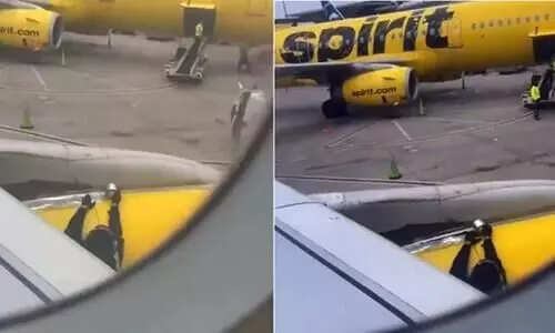Spirit Airlines passenger films an employee putting tape on the plane