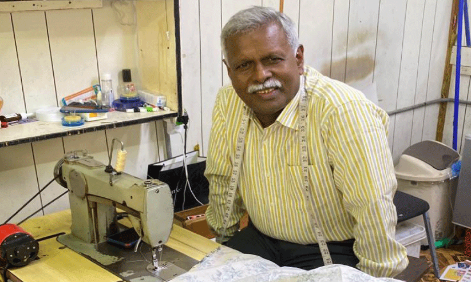 ബി​ൻ ഉം​റാ​നി​ലെ ക​ട​യി​ൽ ത​ന്റെ ബ്ലൂ ​ബേ​ർ​ഡ് ത​യ്യ​ൽ മെ​ഷീ​നി​നൊ​പ്പം ഭാ​സ്ക​ര​ൻ