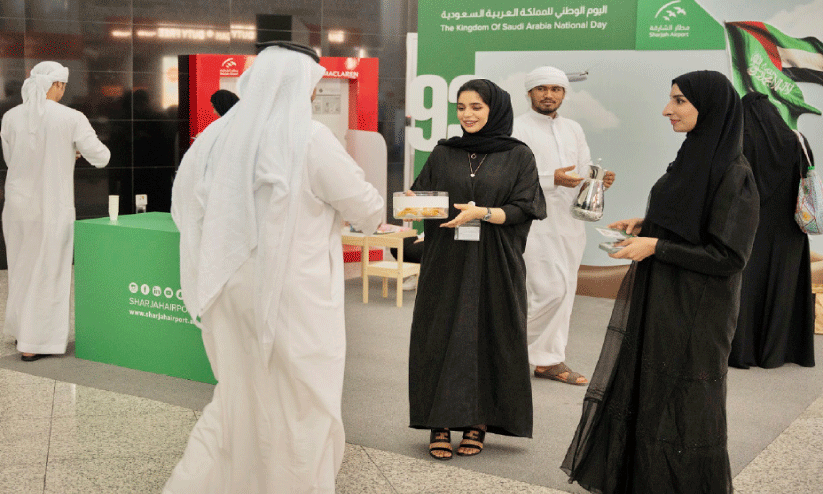 ഷാ​ർ​ജ വി​മാ​ന​ത്താ​വ​ള​ത്തി​ൽ ഇ​റ​ങ്ങി​യ സൗ​ദി പൗ​ര​നെ മ​ധു​രം ന​ൽ​കി സ്വീ​ക​രി​ക്കു​ന്ന ജീ​വ​ന​ക്കാ​ർ