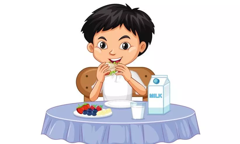 The child sits at the table and eats