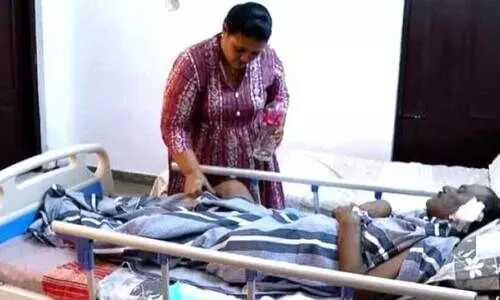 ആ​ശു​പ​ത്രി​യി​ല്‍ ചി​കി​ത്സ​യി​ല്‍ ക​ഴി​യു​ന്ന സ​ജീ​വ​നെ ശു​ശ്രൂ​ഷി​ക്കു​ന്ന ഭാ​ര്യ ര​മ പ്ര​ഭ