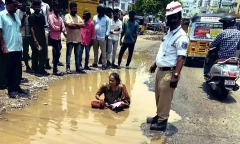 റോഡിലെ കുഴികൾ അടക്കുന്നില്ല; ചെളിയിലിറങ്ങിയിരുന്ന് യുവതിയുടെ പ്രതിഷേധം