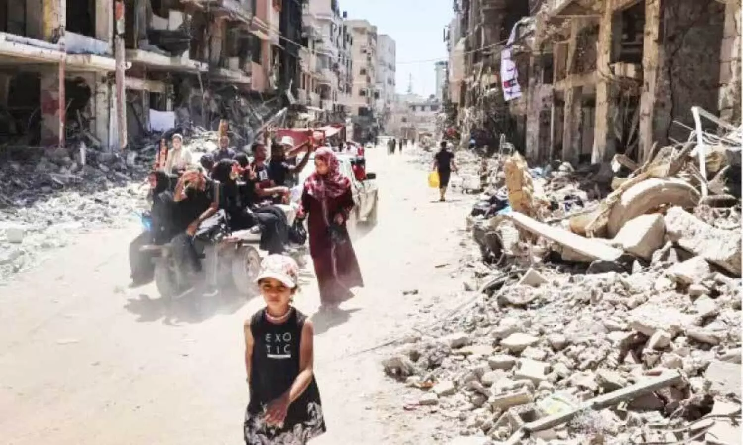 Displaced Palestinians ride in the back of a vehicle along a devastated street in Khan Yunis in the southern Gaza Strip
