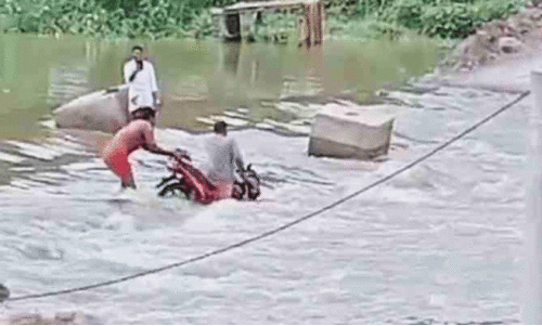 റോഡി​​​ലെ ഒഴുക്കിൽപ്പെട്ട് ബൈക്ക് യാത്രക്കാർ പുഴയിലേക്ക് വീണു