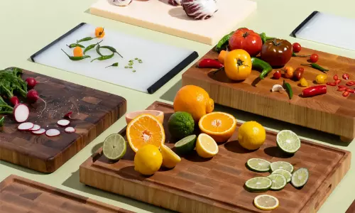 Comparison of plastic, wooden, and stainless steel chopping boards in a kitchen setup.