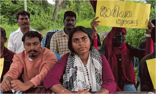 Research scholar Anagha Sashi holding a protest banner during her hunger strike at Malayalam University.