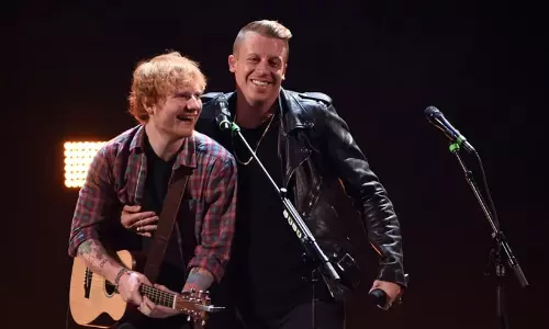 Singer Ed Sheeran performing on stage with macklemore
