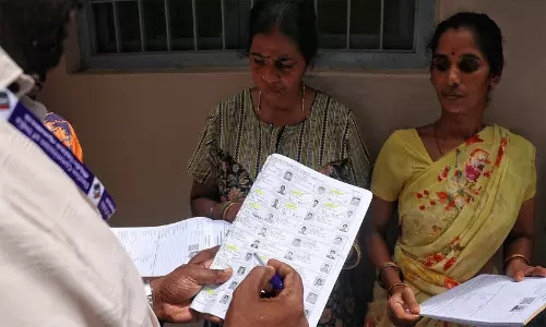 Booth Level Officers in India verifying voter roll entries using a laptop and mobile application.