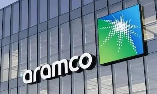 Saudi Aramco headquarters building in Dhahran illuminated at dusk amidst tightened security.
