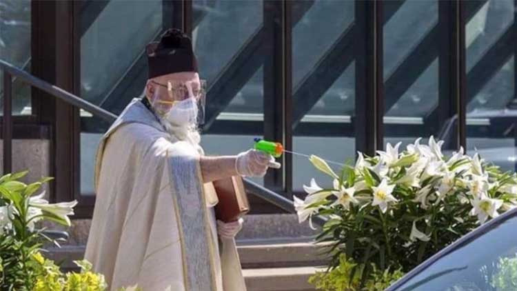 സാമൂഹിക അകലം പാലിക്കാൻ​ കളിത്തോക്കുപയോഗിച്ച്​ പുണ്യതീർത്ഥം തളിച്ചു; വൈദികൻെറ ചിത്രം വൈറൽ